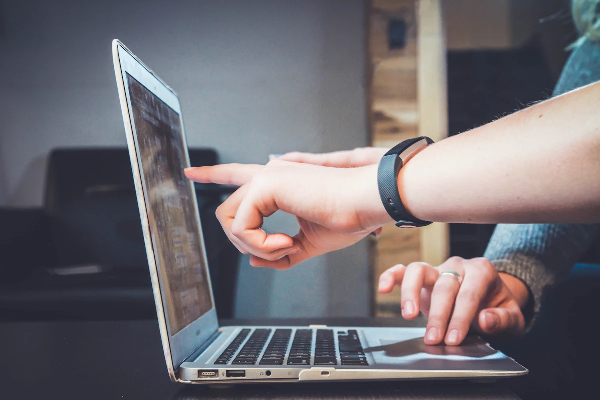 Two people reviewing a website together on a laptop, one pointing at the screen