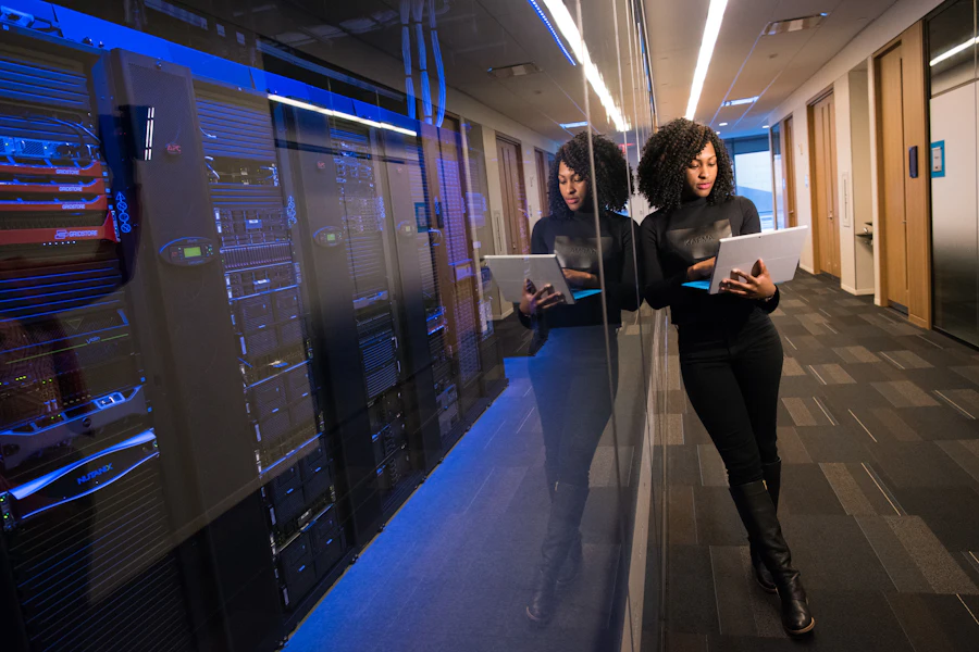 An engineer checking a laptop beside a lit server aisle